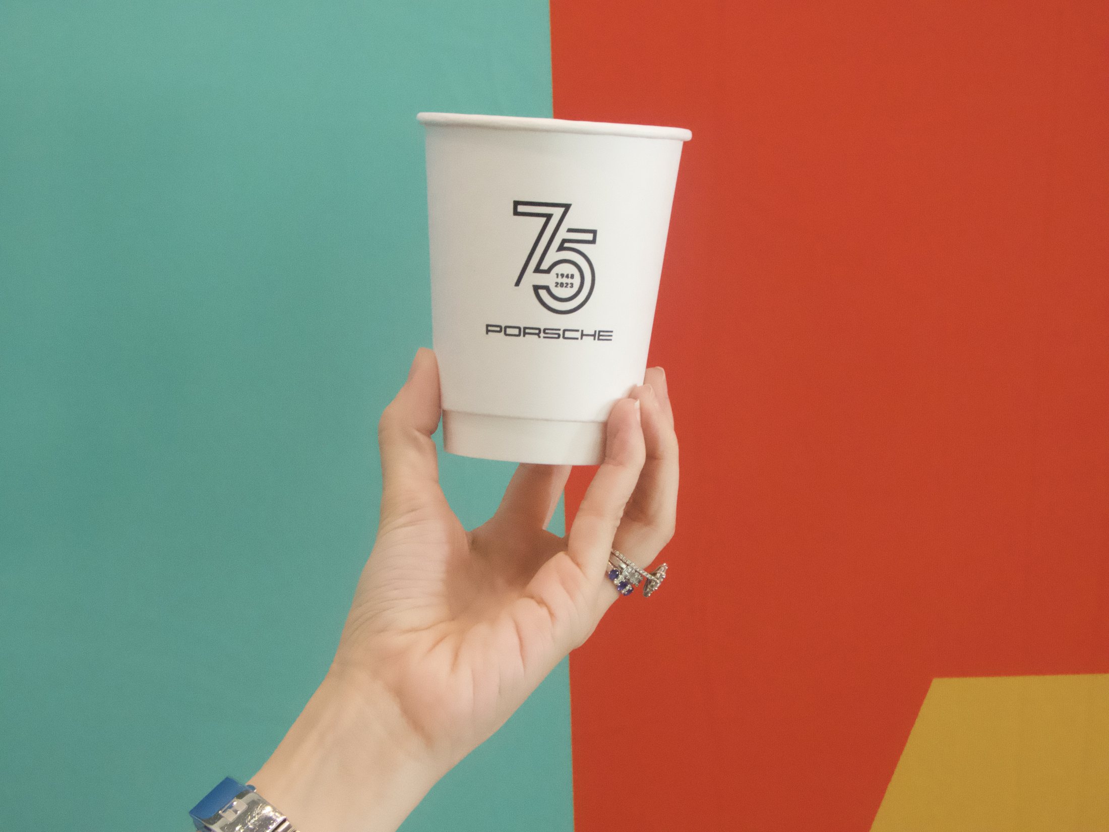 Porsche 75th branded cup against the event color wall